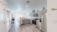 This well-designed single-floor residence offers a seamless blend of modern aesthetics and functional living. The open-concept layout connects the kitchen and living area, creating a spacious, airy atmosphere filled with natural light from large windows throughout.

The kitchen is a standout feature, equipped with a full suite of stainless steel appliances including a French door refrigerator, electric range, built-in microwave, and dishwasher. Gray cabinetry with sleek hardware pairs elegantly with crisp white countertops and a white subway tile backsplash. A peninsula with bar seating and pendant lighting above serves as both a practical workspace and a casual dining hub.

The living room is warm and inviting, featuring light wood-look flooring that runs throughout the unit, a ceiling fan, and a generous window that floods the space with natural light. The welcoming entryway offers a smooth transition into the main living areas.

The bedrooms are comfortable and well-lit, each with wood-look flooring, ceiling fans, and ample natural light. The primary bedroom features a serene, neutral palette, while the secondary bedroom benefits from a bright window and practical storage.

The bathroom is clean and modern, finished with gray vanity cabinetry, white countertops, and a tub-shower combination, maintaining the cohesive, contemporary style found throughout the residence.