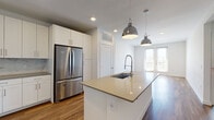 This single-floor residence offers a clean, contemporary design throughout. The kitchen serves as a central highlight, featuring white shaker cabinetry extending to the ceiling, a marble-style tile backsplash, and a full suite of stainless steel appliances including a French door refrigerator, electric range, and built-in microwave. A generously sized island with a quartz countertop and undermount sink anchors the space, illuminated by industrial-style pendant lights. The kitchen flows seamlessly into the living area, which features warm wood-look flooring and French doors that invite natural light and outdoor access.

The bedrooms are finished with plush neutral carpet, ceiling fans, and windows fitted with blinds, providing a comfortable and quiet retreat. Each room offers ample wall space suitable for varied furniture arrangements.

The bathrooms are thoughtfully designed with white cabinetry, quartz countertops, and wood-look flooring. The primary bathroom includes a frameless glass-enclosed walk-in shower with large-format tile and an illuminated vanity mirror above a dual-sink vanity. Recessed lighting throughout maintains a bright, cohesive atmosphere across all rooms.