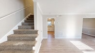 Located at 1357 Sharon Road West in Charlotte, NC, this two-story home offers a practical and well-organized layout across two evenly sized floors. The main level features a bright, open living room with light wood-look flooring, crown molding, and natural light streaming through window blinds. Adjacent to the living area is a dedicated dining space and a compact kitchen outfitted with white cabinetry, light stone countertops, a tile backsplash, and a stainless steel sink — complemented by a pantry for additional storage. A carpeted staircase with clean white trim connects the two floors. Upstairs, three bedrooms offer comfortable living space, each with plush carpeting and ceiling fans. The primary bedroom includes a closet and is well-proportioned for a relaxing retreat. The additional bedrooms also feature ceiling fans and natural light from windows. Three bathrooms service the home, including one with a tiled tub-shower combination, sliding glass door enclosure, patterned tile flooring, and a white vanity. Five closets distributed throughout the home provide ample storage. Outdoors, a private fenced-in area with a patio offers a quiet exterior space. The home is well-suited for everyday living with a clean, neutral aesthetic throughout.