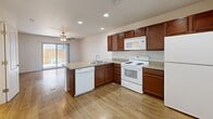 Located in El Paso, TX, this two-story, two-bedroom, three-bathroom home offers a practical and well-appointed layout spread across two floors. The ground floor hosts the main living and kitchen area, where rich dark-wood cabinetry pairs with granite-style countertops and a peninsula island that provides additional prep and seating space. White appliances, including a range, microwave, dishwasher, and refrigerator, complete the kitchen. Recessed lighting and wood-look plank flooring add warmth and brightness throughout the main level. A sliding glass door in the kitchen area opens to an outdoor view, allowing natural light to flow in. A staircase connects the two floors, leading to the upper level where both bedrooms are situated. Each bedroom features plush carpeting, ceiling fans with light fixtures, and windows that invite natural light. The primary bedroom includes a dedicated closet, while the second bedroom offers ample built-in closet storage. Three bathrooms serve the home, each featuring wood-look flooring, a tub-shower combination with built-in shelving, and rich wood-toned vanities with stone-style countertops. The overall aesthetic is clean, neutral, and functional throughout.