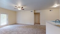 Located at 2650 S Forum Dr in Grand Prairie, TX, this single-floor unit offers a thoughtfully designed layout that balances comfort and functionality. The open living area is finished with plush wall-to-wall carpeting and features a ceiling fan with light fixture, providing a comfortable and airy atmosphere. Neutral warm-toned walls throughout the space lend a clean, versatile backdrop suitable for a variety of interior styles.

The kitchen is a standout feature, outfitted with rich dark cabinetry, stainless steel appliances including a refrigerator and range, and a light-toned countertop with a built-in sink. Wood-look flooring in the kitchen adds a warm contrast to the cabinetry and connects seamlessly to the entryway. A peninsula counter opens the kitchen toward the living area, enhancing the sense of openness and making the space ideal for both everyday living and entertaining.

The bathroom includes a full tub-and-shower combination with clean white tile surround and a shower curtain rod, accompanied by convenient access to a walk-in closet with wire shelving. Additional bedrooms are carpeted and bathed in natural light from windows, offering flexible and comfortable living spaces. Overall, the unit presents a well-maintained, move-in-ready environment with practical finishes throughout.