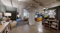 Located in downtown Wichita at 701 E First St N, this two-story urban loft blends industrial character with comfortable living across two well-appointed floors. Exposed pipes, painted concrete structural columns, and polished concrete floors on the lower level establish a raw, warehouse aesthetic that carries throughout the space.

The main floor features an open-plan layout combining the kitchen, dining, and living areas. The kitchen is equipped with wood cabinetry, granite-style countertops, subway tile backsplash, and full black appliances including a dishwasher, range, and refrigerator. A dedicated pantry provides additional storage. The adjacent dining area and living room benefit from large industrial-style windows that invite natural light, with a staircase leading to the upper level.

The upper floor houses the expansive primary bedroom, featuring a ceiling fan, beamed ceilings, plush carpet, and ample closet space. The second bedroom is equally well-sized with carpeting and generous storage. Both bathrooms are thoughtfully finished — one with a wood-tone vanity, granite countertop, decorative tile flooring, and track lighting; the other with wood-look flooring and artistic touches. A dedicated laundry room with concrete floors completes the layout. A welcoming entryway corridor with carpet and lush greenery connects the floors with warmth and style.