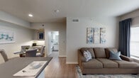 Located at 5750 Curtis Clark Drive in Corpus Christi, TX, this single-floor residence offers a thoughtfully designed layout that balances comfort and functionality. The open-concept living and dining area is anchored by light-toned walls, wood-look flooring, and large windows with floor-to-ceiling drapes that invite natural light throughout the day. A private exterior door provides direct outdoor access from the living space, adding convenience and connectivity to the surroundings.

The galley-style kitchen is efficiently organized with white shaker cabinetry, dark countertops, a double stainless steel sink, and black appliances including a refrigerator and range. Recessed lighting illuminates the workspace, making it both practical and visually clean.

The primary bedroom is a serene retreat featuring a ceiling fan, natural light from a window dressed in blue drapes, and ample space for a full furniture arrangement. A secondary bedroom offers similar comfort with wood-look flooring and generous closet access. Both rooms carry a calm, neutral palette accented with blue tones throughout.

The bathroom is finished with white cabinetry, dark countertops, a well-lit vanity mirror, and light wood-look flooring, maintaining the home's consistent, modern aesthetic. Overall, the space presents a cohesive and comfortable living environment suited for everyday life.