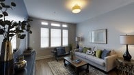 Situated at 515 Montgomery St in the heart of historic Savannah, Georgia, this single-floor residence offers a thoughtfully designed living experience that blends contemporary style with classic Southern character. The living area is a standout feature, showcasing smooth gray walls, warm wood-look flooring, and a clean white ceiling accented by a stylish yellow flush-mount light fixture. A bank of white-shuttered windows with transom panes above floods the room with natural light while maintaining privacy, creating a bright and welcoming atmosphere. The space is well-proportioned, comfortably accommodating a neutral-toned sofa dressed with colorful accent pillows, a rustic industrial-style coffee table on casters, and a sleek accent chair — all arranged atop a layered area rug that adds texture and warmth. Wall-mounted art and a tall floor lamp contribute to the curated, lived-in aesthetic. The overall ambiance is calm and sophisticated, reflecting a balance of functionality and style. Positioned in one of Savannah's most vibrant neighborhoods, the property offers convenient access to the city's renowned squares, dining, and cultural attractions.