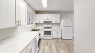 Located at 1700 RT 37 W in Toms River, NJ, this single-floor, one-bedroom, one-bathroom unit offers a thoughtfully designed layout that maximizes functionality. Light-toned luxury vinyl plank flooring flows consistently throughout the space, lending a clean, cohesive aesthetic to every room.

The open-concept living, dining, and kitchen area serves as the heart of the home. The kitchen is well-appointed with crisp white shaker cabinetry, marble-look countertops, white appliances including a gas range and refrigerator, and an in-unit washer — all illuminated by a flush skylight-style ceiling fixture and a window that brings in natural light.

The bedroom features soft sage-green walls, large windows with exterior views, and two closets offering ample storage. Its generous proportions provide a comfortable and private retreat. An additional room with neutral warm-gray walls, recessed lighting, and a wall-mounted HVAC unit adds versatility to the floor plan.

The bathroom is equipped with a full soaking tub, a pedestal-style vanity with a medicine cabinet, tile flooring, and accessibility-friendly grab bars, ensuring both comfort and practicality. A dedicated entrance area completes the layout. Overall, the unit presents a clean, move-in-ready interior with a bright, neutral palette throughout.