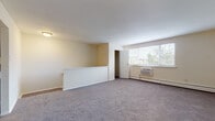 This single-floor residence offers a practical and comfortable layout across several distinct living areas. The spacious living room is finished with neutral-toned carpet and features a large multi-pane window that draws in natural light while offering views of surrounding greenery. A wall-unit air conditioner and baseboard heating ensure year-round comfort. A half-wall partition adds subtle architectural definition to the space, while an adjacent closet provides convenient storage.

The kitchen is well-equipped with dark espresso cabinetry, light stone-look countertops, and a full suite of stainless steel appliances, including a refrigerator, electric range, built-in microwave, and dishwasher. Warm hardwood-style flooring and track lighting complete the functional yet modern aesthetic.

The bedroom is generously sized, carpeted, and features a wide double sliding-door closet along with a window and wall-unit air conditioner. Baseboard heating is also present.

The bathroom is finished with neutral large-format tile flooring and white subway tile wainscoting, creating a clean, classic appearance. A vanity with dark cabinetry provides storage. The overall ambiance of the residence is bright, neutral, and move-in ready.