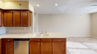 Located at 3801 S Water Tower Pl in Mount Vernon, Illinois, this single-story, one-bedroom, one-bathroom residence offers a well-designed and functional layout. The open-concept kitchen and living area forms the heart of the home, featuring rich warm-toned cabinetry, a large kitchen island with a double sink and generous counter space, stainless steel appliances including a refrigerator, electric range, microwave, and dishwasher, and recessed lighting overhead. Tile flooring in the kitchen transitions seamlessly into plush carpeting in the living area, creating a comfortable and inviting atmosphere. The bedroom is a comfortably sized retreat, finished with the same soft carpeting, warm neutral wall tones, and a ceiling fan with light fixture. A window allows natural light to fill the room, and a dedicated closet provides ample storage. The bathroom is clean and efficiently arranged, featuring a combination tub and shower unit with tile flooring. Additional practicality is provided by a dedicated in-unit laundry area. Throughout the space, neutral earth-tone walls and white trim lend a cohesive, understated aesthetic that is easy to personalize.