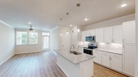This thoughtfully designed single-story residence offers 2 bedrooms and 2 bathrooms within a bright, efficiently laid-out floor plan. The open-concept kitchen and living area serves as the heart of the home, anchored by a central granite-topped island with an undermount sink and pendant lighting. The kitchen features crisp white shaker cabinetry, a marble-style tile backsplash, stainless steel appliances, and recessed lighting, all accented by crown molding. The adjacent living room offers light wood-look flooring, crown molding, a ceiling fan, and large windows that fill the space with natural light and views of greenery outside. Both bedrooms are carpeted and include ceiling fans, with the primary bedroom offering generous proportions and access to a spacious walk-in closet equipped with wire shelving systems. The bathrooms are finished with granite countertops, white cabinetry, and wood-look luxury vinyl flooring. One bathroom features a subway tile tub-and-shower surround. A connecting hallway links the private and common areas, and two closets provide additional storage throughout the home. The overall aesthetic is clean, contemporary, and move-in ready.