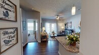 This single-floor residence offers a thoughtfully designed open-concept layout that connects the kitchen, dining, and living areas seamlessly. The kitchen features rich dark cabinetry, granite-style countertops, a subway tile backsplash, stainless steel appliances, and durable wood-look flooring that extends into the main living areas, creating a cohesive aesthetic throughout.

The living room is generously proportioned, bathed in natural light from large windows and a glass sliding door that opens to a private balcony. A ceiling fan overhead adds comfort, while the neutral gray walls provide a versatile backdrop. Framed artwork and stylish furnishings complement the space's warm, welcoming ambiance.

The primary bedroom is a comfortable retreat, outfitted with plush carpet, a ceiling fan, ample natural light from a large window, and sufficient space for a full furniture arrangement. A second bedroom, also carpeted with a ceiling fan, offers similar comfort. The bathroom features matching dark cabinetry, granite-style countertops, wood-look flooring, and direct access to a walk-in closet area.

A practical in-unit laundry area is conveniently accessible from the living space, adding everyday functionality to this well-rounded residence.