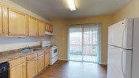 Located at 10714 Abercorn Ext in Savannah, Georgia, this single-floor residence offers a practical and comfortable layout throughout. The kitchen is well-appointed with light oak cabinetry, dark granite-style countertops, and a full suite of appliances including a white refrigerator, electric range with overhead ventilation, and a dishwasher. Hardwood-style flooring runs through the kitchen, which also features a sliding glass door fitted with vertical blinds that opens to an outdoor space, allowing natural light and exterior views to fill the room. A textured ceiling with flush lighting adds to the functional design of the kitchen area. The bedrooms are carpeted and finished in warm neutral tones, each equipped with a ceiling fan with built-in light fixture to promote comfort year-round. Windows in the bedrooms invite in natural light and views of the surrounding neighborhood. The textured ceilings continue throughout, lending a consistent aesthetic to the space. Clean white trim and neutral wall colors provide a versatile backdrop throughout the residence, making it easy to personalize. Overall, the space presents a straightforward, move-in-ready layout suited for everyday living in the Savannah, Georgia area.