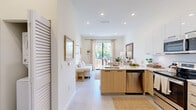 Located at 16395 Biscayne Blvd in North Miami Beach, this well-designed one-bedroom, one-bathroom residence offers a clean, contemporary aesthetic throughout. The open-concept layout connects the kitchen and living area seamlessly, creating an efficient and inviting flow. The kitchen is a standout feature, outfitted with light wood cabinetry, white upper cabinets, a white quartz peninsula with an undermount sink, and a full suite of stainless steel appliances including a refrigerator with ice maker, electric range, microwave, and dishwasher. Recessed lighting and large sliding glass doors flood the living area with natural light, while access to a private outdoor patio extends the living space beyond the interior. The bedroom is a calm retreat, featuring a window with lush greenery views, recessed and ceiling fan lighting, and ample space for furnishings. A dedicated closet provides practical storage. The bathroom is finished with a light wood vanity, white countertop, large-format marble-style tile surrounding the soaking tub and shower combination, and neutral tile flooring. Soft tones, tile flooring throughout, and thoughtful details give this residence a cohesive, modern South Florida character.