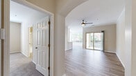 This well-appointed 2-bedroom, 2-bathroom residence at 350 Whitewater Dr in Bolingbrook, IL offers a thoughtfully designed single-floor layout. The open-concept living and dining area is highlighted by light hardwood-style flooring, crown molding, a ceiling fan, and a sliding glass door that leads to a private balcony, filling the space with natural light. An elegant arched passageway connects the living area to the rest of the unit, adding a refined architectural touch. The kitchen is equipped with white shaker cabinetry, stainless steel appliances including a refrigerator, range, microwave, and dishwasher, complemented by light countertops and matching hardwood-style flooring. Both bedrooms feature plush carpeting, ceiling fans, and windows with exterior views. The generously sized primary bedroom includes a walk-in closet with wire shelving for ample storage. Both bathrooms are finished with wood-look flooring, white cabinetry with brushed nickel hardware, light countertops, and tiled tub-shower combinations. A hallway connects the main living areas to the bedrooms, providing a clear and functional flow throughout the residence.