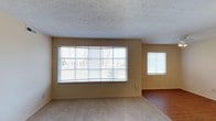 This single-floor residence offers a comfortable and functional layout with 2 bedrooms and 2 bathrooms. The living area is a standout feature, highlighted by a large multi-pane bay-style window that floods the room with natural light and offers views of the surrounding outdoor environment. A secondary window on the adjacent wall further enhances the bright and airy atmosphere of the space. The living area is finished with plush wall-to-wall carpeting, providing a warm and inviting feel underfoot. Transitioning further into the home, hardwood flooring adds a classic and durable touch to the additional areas. The walls are painted in a soft, neutral warm tone, creating a welcoming ambiance that complements a variety of décor styles. The textured ceiling adds a subtle architectural detail throughout the space. The overall layout is designed to maximize functionality while maintaining an open and connected feel between rooms, making it an ideal space for comfortable everyday living.