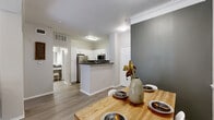 Located at 2350 Bagby St in Houston's Midtown neighborhood, this one-bedroom, one-bathroom residence offers a thoughtfully designed single-floor layout. Light wood-look flooring flows throughout, complemented by crown molding and a neutral color palette accented by slate-gray feature walls.

The open-concept living and dining area is anchored by a ceiling fan and French doors that invite natural light and offer outdoor views. The dining space connects seamlessly to the kitchen, which features white shaker-style cabinetry, dark countertops, and a full suite of stainless steel appliances including a refrigerator, range, microwave, and dishwasher — all centered around a convenient peninsula.

The bedroom is a comfortable retreat with a ceiling fan, a large window with outdoor views, and ample space for a full furniture arrangement. A hallway connects the bedroom to the well-appointed bathroom, which includes a lengthy dark-countertop vanity with white cabinetry, a large mirror, and a separate tub and shower area.

Additional highlights include a dedicated closet, an in-unit laundry room with a full-size washer and dryer, and an entrance hallway. The overall ambiance is modern and cohesive, making efficient use of every room throughout the residence.