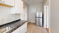 Located at 2014 Park St in Hartford, CT, this two-bedroom, one-bathroom residence offers a compact and efficiently designed single-floor layout. Warm, polished hardwood floors run throughout the bedrooms and main living areas, reflecting natural light that pours in through multiple windows dressed with blinds. The spacious primary bedroom provides generous room for furnishings, while the second bedroom offers a cozy and functional space, both featuring neutral gray walls and clean white trim.

The kitchen is thoughtfully appointed with white cabinetry, dark granite countertops, a stainless steel refrigerator, a gas range, and a built-in microwave. Light-toned luxury vinyl plank flooring, a stainless steel sink, and a window overlooking the outdoors complete the galley-style kitchen. A classic cast-iron radiator adds a charming, period-appropriate detail to the space.

The bathroom features large-format marble-style tile walls and flooring, a walk-in shower, a white vanity with sink, and a mirror cabinet, presenting a clean and modern aesthetic. A connecting hallway ties the rooms together seamlessly. The overall ambiance is bright, clean, and move-in ready, with a timeless character well-suited to comfortable everyday living.
