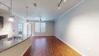 This single-floor residence offers a thoughtfully designed open layout that balances comfort and functionality throughout its living spaces. The main living and dining area is a standout feature, showcasing warm, rich hardwood-style flooring that extends seamlessly across the space. Crown molding frames the ceiling, adding a refined architectural detail, while a ceiling fan provides practical comfort. Track lighting along the ceiling offers versatile illumination, and a window allows natural light to brighten the room. A dark-topped kitchen counter serves as a natural divider between the living area and kitchen.

The kitchen is well-appointed with dark espresso cabinetry, granite countertops, a tile backsplash, and stainless steel appliances including a refrigerator, range, and microwave. A set of double doors provides convenient pantry or closet storage nearby.

The bedrooms are finished with plush carpeting and ceiling fans, creating a comfortable and quiet retreat. Each room benefits from natural light through windows with blinds. A spacious walk-in closet features multiple shelving units and hanging rods for generous storage.

The bathroom is neatly finished with tile flooring, a granite-topped dark vanity with a large mirror, and a tiled tub-shower combination equipped with grab bars for added accessibility.