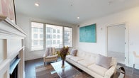 Located at 936 N High St in Columbus, Ohio's vibrant Short North neighborhood, this single-floor residence offers a thoughtfully designed open-concept layout with high-end finishes throughout. The bright living area features dark hardwood floors, large windows that invite abundant natural light and urban views, and a cozy fireplace that serves as a focal point. A seating nook adjacent to the living room provides an ideal spot for relaxing while enjoying city views through oversized windows.

The gourmet kitchen is a standout feature, showcasing custom gray cabinetry, a marble-style mosaic tile backsplash, stainless steel appliances including a professional-grade range and refrigerator, and a generously sized center island with a white quartz countertop and bar seating beneath polished pendant lights. Dark hardwood flooring continues seamlessly from the living area into the kitchen.

The bedrooms are carpeted for comfort and benefit from natural light through well-positioned windows. The bathrooms are elegantly appointed with light tile flooring, glass-enclosed walk-in showers, gray vanities with white quartz countertops, and backlit mirrors. The primary bath includes a dual-sink vanity and convenient access to a walk-in closet, completing this refined urban residence.