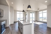 Located on Oakdale Blvd in Tiffin, Iowa, this well-appointed single-story home offers three bedrooms, two bathrooms, and a thoughtfully designed open layout. Light-toned luxury vinyl plank flooring flows throughout, complementing the clean, neutral color palette that defines the home's modern aesthetic.

The living room is a standout space, anchored by expansive floor-to-ceiling windows that flood the area with natural light and frame sweeping views of the surrounding landscape. A ceiling fan adds both style and function. The kitchen features white shaker-style cabinetry, granite countertops, stainless steel appliances including a refrigerator, range, and over-the-range microwave, and a central island with pendant lighting.

The primary bedroom is generously sized with wide windows offering scenic outdoor views and a ceiling fan overhead. It connects to a dedicated walk-in closet with wire shelving and a private en-suite bathroom featuring dual sinks set in granite countertops, white cabinetry with black hardware, and wood-look flooring. The second full bathroom mirrors this refined style, offering a double vanity with granite counters and a walk-in shower. Two additional bedrooms provide comfortable accommodations, each with natural light and outdoor views.