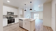 Located at 617 N Lancaster Ave in Dallas, TX, this thoughtfully designed one-bedroom, one-bathroom residence offers a clean, contemporary aesthetic across a single level of comfortable living space. Light-toned wood-style flooring runs throughout, creating a cohesive and modern feel.

The open-concept kitchen is a standout feature, anchored by a central island with a built-in sink and pendant lighting overhead. White shaker cabinetry, quartz countertops, a tiled backsplash, and a full suite of stainless steel appliances — including an electric range, over-the-range microwave, dishwasher, and refrigerator — make this kitchen as functional as it is attractive.

The kitchen flows seamlessly into the living room, which is brightened by a sliding glass door that opens to an outdoor balcony, inviting natural light and views of the surrounding neighborhood. The bedroom is a well-proportioned retreat with a ceiling fan, dual windows for natural light, and direct access to a closet. A second closet provides additional storage.

The bathroom features a sleek white vanity with an under-mount sink, an illuminated mirror, and wood-style flooring that continues the home's design language. A dedicated laundry area completes this efficiently planned residence.