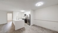 This 2-bedroom, 2-bathroom single-floor residence offers a clean, modern aesthetic throughout, highlighted by light wood-style flooring and a bright, neutral color palette. The open-concept kitchen and living area serves as the heart of the home, where a large white quartz peninsula with an undermount sink and a contemporary pull-down faucet anchors the space. The kitchen is equipped with stainless steel appliances — including a refrigerator, electric range, and over-the-range microwave — complemented by white shaker cabinetry, a tile backsplash, and dark espresso lower cabinets for contrast. The living area flows naturally from the kitchen and features a sliding glass door with vertical blinds that opens to an outdoor space, filling the room with natural light. Both bedrooms are well-sized, with the primary bedroom offering a comfortable footprint, a ceiling fan with light fixture, and a dedicated closet. The second bedroom also includes a ceiling fan and a window with outdoor views. Each of the two bathrooms features a full tub-shower combination with tiled surround, a white vanity with quartz countertop, and dark wood cabinetry. Two closets provide ample storage throughout the residence.