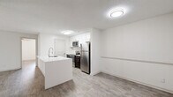 This 2-bedroom, 2-bathroom single-floor residence offers a clean, modern aesthetic throughout, highlighted by light wood-style flooring and a bright, neutral color palette. The open-concept kitchen and living area serves as the heart of the home, where a large white quartz peninsula with an undermount sink and a contemporary pull-down faucet anchors the space. The kitchen is equipped with stainless steel appliances — including a refrigerator, electric range, and over-the-range microwave — complemented by white shaker cabinetry, a tile backsplash, and dark espresso lower cabinets for contrast. The living area flows naturally from the kitchen and features a sliding glass door with vertical blinds that opens to an outdoor space, filling the room with natural light. Both bedrooms are well-sized, with the primary bedroom offering a comfortable footprint, a ceiling fan with light fixture, and a dedicated closet. The second bedroom also includes a ceiling fan and a window with outdoor views. Each of the two bathrooms features a full tub-shower combination with tiled surround, a white vanity with quartz countertop, and dark wood cabinetry. Two closets provide ample storage throughout the residence.