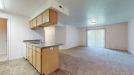 This 2-bedroom, 2-bathroom single-floor residence in Riverton, Utah, offers a practical and comfortable layout designed for everyday living. The open-concept design connects the kitchen and living area seamlessly, creating a spacious and functional common area. The kitchen is well-appointed with light wood cabinetry, ample upper and lower cabinet storage, a double-basin sink, tile flooring, and white appliances including a range and refrigerator. A peninsula counter provides additional workspace and a natural transition into the living area. The living room features plush wall-to-wall carpeting and a large sliding glass door fitted with vertical blinds, allowing natural light to fill the space and providing access to the outdoors. Both bedrooms are generously sized, each with soft carpeting, neutral white walls, and closet access. Windows with horizontal blinds bring in natural light. The two bathrooms include tile flooring, vanity cabinetry with countertop sinks, and a tub-shower combination. Throughout the unit, the consistent use of light tones and neutral finishes creates a clean, understated ambiance well-suited for comfortable residential living.
