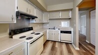 This two-story residence at 1901 S Goyer Rd in Kokomo, Indiana, offers a practical and functional layout across two floors of comparable size. Neutral warm-beige tones carry throughout the space, lending a consistent and cohesive feel from room to room.

The main floor houses the kitchen, which features light wood-look hard surface flooring, white cabinetry extending to the upper walls for generous storage, a coil-burner electric range, dishwasher, and a double sink positioned beneath a window that brings in natural light. A separate dining or utility area adjacent to the kitchen shares the same flooring and provides additional flexibility. The main living area is carpeted, benefits from a ceiling fan, and includes sliding glass doors that fill the room with natural light while offering outdoor access.

The upper floor is dedicated to the four bedrooms, all finished with carpet and warmed-beige walls. The generously sized primary bedroom stands out with dual closets and a window overlooking the exterior. Additional bedrooms are well-proportioned, each with windows providing natural light. The three bathrooms are distributed across both floors, featuring tub-shower combinations, vanities with stone-patterned countertops, and simple, clean fixtures throughout.