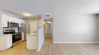 Located at 833 Misty Hallow Ln. in Columbus, Ohio, this single-floor, 2-bedroom, 2-bathroom residence offers a functional and well-appointed layout with a clean, neutral aesthetic throughout. The combined kitchen and living area forms the heart of the home, where light wood-style vinyl flooring, a textured ceiling, and a half-wall peninsula with a light granite-style countertop define the space. The kitchen is equipped with stainless steel appliances — including a refrigerator, range, microwave, and dishwasher — paired with white shaker-style cabinetry and a classic subway tile backsplash. The living area is open and airy, with ample room for comfortable furnishings. A hallway connects the main living space to the bedrooms and bathrooms. The spacious primary bedroom features plush wall-to-wall carpeting, a natural window, a textured ceiling, and a built-in closet with shelving. The second bedroom also offers light wood-style flooring and a window for natural light. Both bathrooms are finished with white vanities featuring light stone-style countertops and wood-style flooring. The entrance and a dedicated closet round out the thoughtfully organized floor plan, making this a practical and inviting home.