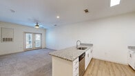 Located at Windsor Hill Blvd in North Charleston, SC, this single-floor residence offers four bedrooms and two bathrooms within a well-designed, efficient floor plan. The open-concept kitchen is a standout feature, boasting granite countertops, white shaker-style cabinetry with brushed nickel hardware, a subway tile backsplash, and a full suite of stainless steel appliances including a refrigerator, range, and microwave. A center island with a built-in sink and dishwasher provides additional prep space and connects seamlessly to the living area, which features plush carpeting, a ceiling fan, and French doors that invite natural light. The bedrooms are carpeted and bright, each with windows fitted with blinds; the spacious primary bedroom includes a ceiling fan and ample room. Both bathrooms are finished with granite-topped white vanities and light wood-look flooring, maintaining a consistent, clean aesthetic throughout. The neutral color palette and modern finishes create a cohesive, move-in-ready atmosphere suited for comfortable everyday living.
