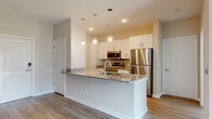 Located at 719 Lantern Walk Dr in Little River, SC, this well-appointed single-floor residence offers a bright and modern living experience with a thoughtfully designed open-concept layout. The main living area features light-toned hardwood-style flooring, neutral warm walls, and a ceiling fan, creating an inviting and airy atmosphere. A sliding glass door opens to a private balcony, flooding the space with natural light and providing outdoor views of the surrounding community.

The kitchen is a standout feature, showcasing granite countertops, crisp white shaker cabinetry, a tiled backsplash, and a full suite of stainless steel appliances including a refrigerator, range, and microwave. A large peninsula with an undermount sink and elegant pendant lighting overhead makes it ideal for both meal preparation and casual dining.

The bedroom offers plush carpeting, a generous closet, and a bright window with outdoor views, lending a comfortable and restful ambiance. The full bathroom is well-appointed with granite-topped white vanity cabinetry, a tub-shower combination, and hardwood-style flooring. A dedicated utility area houses a stacked washer and dryer along with a water heater, adding everyday convenience to the home.