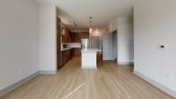 This well-appointed single-floor residence at 901 River Rd in Charlottesville, Virginia offers a thoughtfully designed open-concept layout with modern finishes throughout. Light wood-tone flooring flows continuously across all rooms, creating a cohesive and airy feel.

The kitchen serves as a central hub of the space, featuring rich wood-grain cabinetry, a white quartz island with pendant lighting overhead, stainless steel appliances including a refrigerator, microwave, and range, and a classic white subway tile backsplash. Track lighting adds a contemporary touch and ensures ample illumination for cooking and entertaining.

The living and bedroom areas are bright and welcoming, with large windows dressed with blinds that invite natural light while maintaining privacy. Ceiling fans are installed in multiple rooms, contributing to year-round comfort. The bedrooms offer clean, neutral walls and generous proportions, with one bedroom featuring direct access to the bathroom.

The bathroom is finished with light wood-tone flooring, a warm walnut-toned vanity with a white countertop, a large mirror, and a walk-in shower. The layout is functional and well-organized, with additional doors providing convenient access to other areas of the residence.

Overall, the space presents a clean, contemporary aesthetic with quality materials and a practical floor plan suited to comfortable everyday living in Charlottesville.
