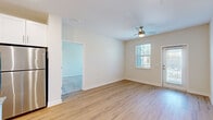 Located at 7045 Pine Forest Rd in Pensacola, Florida, this single-floor residence offers 2 bedrooms and 2 bathrooms with a thoughtfully designed open-concept layout. The kitchen serves as a central highlight, featuring crisp white shaker cabinetry, granite countertops, a classic subway tile backsplash, and a full suite of stainless steel appliances including a range, over-the-range microwave, dishwasher, and refrigerator. A central island with pendant lighting above provides additional prep space and connects seamlessly to the living area, which is finished with light hardwood-style flooring and a ceiling fan. Natural light flows in through windows and a glass-panel door leading to an outdoor area. Both bedrooms are carpeted and include ceiling fans and windows with blinds. The generously sized primary bedroom connects to a private en-suite bathroom with a granite-topped vanity, and features a walk-in closet with wire shelving for organized storage. The en-suite bathroom is finished with light hardwood-style flooring and a glass-enclosed shower. A second bedroom and additional bathroom round out the floor plan. Two dedicated closets offer practical storage throughout the home.