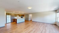 Located at 1204 Dayton Street in Mayville, Wisconsin, this single-floor, 3-bedroom, 2-bathroom home offers a well-designed layout with modern finishes throughout. The open-concept kitchen and living area serves as the heart of the home, featuring warm wood-grain cabinetry extending floor to ceiling, crisp white countertops, a central island, and a full suite of stainless steel appliances including a refrigerator, range, microwave, and dishwasher. Light hardwood flooring flows seamlessly through the main living areas, complementing the neutral, warm-toned walls and clean-lined design. The living area is generously proportioned, with large windows that invite abundant natural light and offer pleasant outdoor views of the surrounding greenery. The three bedrooms are comfortably sized, with the primary bedroom providing a well-appointed retreat. Bedrooms feature hardwood flooring, built-in closets with sliding doors, and easy access to the hallway. The two bathrooms are finished with wood-toned vanities, illuminated mirrors, textured tile flooring, and a full soaking tub with grab bars. An attached garage with an automatic opener and a concrete floor provides convenient and spacious vehicle storage. This home combines practical layout and modern aesthetics throughout.