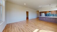 Located at 13155 SW 68th Parkway in Tigard, Oregon, this well-appointed 2-bedroom, 2-bathroom residence offers a clean, contemporary design throughout. Warm-toned luxury vinyl plank flooring runs continuously across every room, creating a cohesive and inviting atmosphere.

The open-concept kitchen and living area serves as the heart of the home, featuring a stylish kitchen island with wood-grain cabinetry, white quartz countertops, and pendant lighting. The living area is generously proportioned, offering ample space for both relaxing and entertaining.

The primary bedroom is a comfortable retreat, bathed in natural light through large windows that frame views of the surrounding Pacific Northwest landscape, including mature evergreen trees. Both bedrooms are supported by dedicated walk-in closets outfitted with wire shelving systems for practical and organized storage.

Each of the two bathrooms is finished with the same modern aesthetic — warm wood-tone vanities, white quartz countertops, large mirrors, and a full tub-shower combination. Recessed and vanity lighting ensure bright, functional spaces.

A connecting hallway links all rooms efficiently, while the bright, neutral color palette throughout enhances the sense of openness. Corner windows in the living area flood the space with abundant natural light and provide treetop and neighborhood views, making this a bright and comfortable Tigard residence.