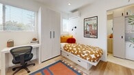 Located at 2601 S Hoover St in Los Angeles, this efficiently designed studio is ideally situated near the University of Southern California. The single-level layout makes excellent use of its compact footprint, offering a cohesive and functional living environment finished with light oak-toned hardwood flooring and crisp white walls throughout.

The sleeping area is thoughtfully arranged with a platform bed featuring built-in drawers for additional storage, a full-height wardrobe with a clean, contemporary finish, and a dedicated desk workspace positioned beside a natural-light window — ideal for studying or remote work. A wall-mounted split AC unit ensures year-round comfort.

The kitchen is well-appointed with flat-front cabinetry in a soft off-white finish, white subway tile backsplash, and a full suite of stainless steel appliances including a gas range, microwave, and dishwasher. A bright window brings in natural light and keeps the space feeling open.

The bathroom features marble-look tile flooring, a walk-in glass-enclosed shower with built-in shelving, a vanity with under-sink storage, and a clean, all-white palette that enhances the sense of space. The entryway is welcoming and uncluttered, with room for a mounted display and a statement indoor plant, setting a fresh tone upon arrival.