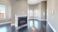 Located in Washington, DC's New Jersey Avenue NW corridor, this 2-bedroom, 2-bathroom residence offers a thoughtfully designed single-floor layout. The open-concept living and dining area is a standout feature, anchored by a marble-surround fireplace with a classic white mantle and rich, dark hardwood floors that reflect natural light throughout. Soaring ceilings with recessed lighting and a chandelier add volume and warmth, while curved walls contribute an elegant architectural touch. Large windows frame views of the surrounding DC streetscape, filling the space with natural light. The kitchen is efficiently designed with white shaker-style cabinetry, dark granite countertops, a gas range, and stainless steel appliances. Both bedrooms are generously sized, carpeted for comfort, and feature ample closet space—including three closets throughout the unit. The spacious primary bedroom offers room to accommodate a full furniture suite. Two full bathrooms with neutral tile finishes provide functional convenience. A dedicated laundry area and hallway complete the layout. The warm, neutral color palette throughout creates a cohesive and inviting atmosphere, making this a well-rounded urban residence.