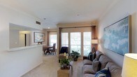 This well-appointed 2-bedroom, 2-bathroom residence in Muscat offers comfortable single-floor living with a thoughtfully designed layout. The open-plan living and dining area serves as the heart of the home, bathed in natural light streaming through large windows dressed with elegant drapes. Crown molding adds a refined architectural touch to the neutral-toned walls and ceilings, lending the space a polished, cohesive feel.

The living area is generously proportioned, featuring plush carpeting underfoot and ample space for relaxed seating arrangements. Decorative accents, including potted plants and tasteful wall art, contribute to the warm and inviting ambiance. A floor lamp and natural light work in harmony to keep the space bright throughout the day.

The dining area is seamlessly connected to the living space, offering a dedicated setting for meals with a classic round dining table and upholstered chairs. A pass-through opening connects to the kitchen, enhancing the open and airy feel of the shared living spaces.

Overall, the residence strikes a balance between functionality and comfort, with neutral finishes, carpeted flooring, and an abundance of natural light creating a welcoming atmosphere suited for everyday living.