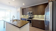 Located at 3410 Alexander Rd in Atlanta's prestigious Buckhead neighborhood, this modern single-floor residence showcases contemporary design and high-end finishes throughout. The gourmet kitchen is a standout feature, equipped with rich dark-wood cabinetry extending to the ceiling, granite countertops, a glass tile backsplash, and a full suite of stainless steel appliances including a French door refrigerator, electric range with microwave, and dishwasher. A large center island with a dark stone countertop and undermount sink serves as both a prep area and casual dining space, illuminated by stylish pendant lighting. The open-concept layout flows seamlessly from the kitchen into the living areas, where wide-plank hardwood flooring and floor-to-ceiling windows flood the space with natural light and offer sweeping Atlanta skyline views. The bedrooms are generously proportioned, featuring plush carpeting, ceiling fans, and large windows that continue the city views. The bathrooms are finished with large-format tile flooring, soaking tub and shower combinations, and clean white tile surrounds accented with neutral taupe tile detailing. Built-in shelving and louvered-door closets provide ample storage throughout. The overall ambiance is clean, bright, and urban-modern, making this a refined city residence.