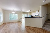 Located on Walsh's Way in Marysville, WA, this two-story, 4-bedroom, 3-bathroom home offers a well-organized layout spread across two floors. The main level features an open-concept living and dining area with warm light wood-style flooring, neutral warm-toned walls, and large windows that invite abundant natural light and views of surrounding greenery. A pendant light fixture anchors the dining space, while a sliding glass door provides access to the outdoors. The kitchen is defined by a peninsula with dark countertops, crisp white cabinetry, and stainless steel appliances including a refrigerator, range, and microwave. The upper level houses all four bedrooms, including a generously sized primary bedroom, all carpeted for comfort and connected by a central hallway. Each bedroom features neutral walls and good natural light. The three bathrooms are clean and functional, with one featuring a double-sink vanity, wood-style flooring, and a shower-tub combination. Additional conveniences include dedicated laundry and multiple closets throughout. The home's layout, modern finishes, and connection to natural surroundings make it a practical and comfortable residence.