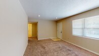 This single-story space is thoughtfully laid out across several well-defined rooms, offering a practical and comfortable floor plan. The living area features neutral-toned walls, plush carpeting, recessed lighting, and a textured ceiling, creating a clean and understated atmosphere. A wide window allows natural light to fill the room, enhancing its open feel.

The kitchen is equipped with rich, warm-toned cabinetry, dark granite-style countertops, and a full suite of appliances including an electric range, refrigerator, dishwasher, and microwave. Light tile flooring runs throughout the kitchen and into the adjacent dining area, which benefits from a sliding glass door that opens to an outdoor view, bringing in additional natural light.

The bedrooms are carpeted and feature ceiling fans with integrated lighting, neutral walls, and windows with blinds. At least one bedroom includes a closet with paneled doors. The bathrooms are finished with tile flooring, white tub-shower combinations, single-sink vanities with warm wood cabinetry, and chrome fixtures, offering a clean and functional design throughout.
