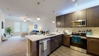 Located at 9611 Kona Village Dr in Riverview, FL, this single-floor residence offers a thoughtfully designed open-concept layout with modern finishes and a warm, welcoming ambiance. The kitchen is a standout feature, equipped with rich dark-wood cabinetry, stainless steel appliances including a refrigerator, range, and microwave, and a generous white quartz island with bar seating. Pendant lighting illuminates the space, which transitions seamlessly into the dining and living areas. The spacious living room is carpeted and bathed in natural light from large windows with blinds, and features crown molding and a ceiling fan overhead. Two well-sized bedrooms each offer plush carpeting, closet space, and windows that bring in ample natural light. Both bathrooms are finished with dark-wood vanities, white countertops, wood-look plank flooring, and large mirrors. The primary bathroom features a double-sink vanity, while the secondary bathroom includes a tub-shower combination. Throughout the residence, a consistent palette of neutral tones, wood-look flooring in the kitchen and bathrooms, and quality fixtures create a cohesive and refined living environment.