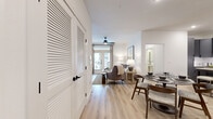 This thoughtfully designed single-floor residence offers a cohesive and modern living experience across one bedroom, two bathrooms, a dedicated office, and an open-concept living and dining area. Light wood-tone flooring flows seamlessly throughout, complemented by a neutral, white-toned palette that enhances the sense of openness.

The entry hallway is flanked by louvered double-door closets, leading into a combined living and dining space. The living room features a ceiling fan, large French doors that invite abundant natural light, and views of the surrounding exterior. The kitchen is outfitted with grey shaker cabinetry, granite countertops, a geometric tile backsplash, and stainless steel appliances, offering both style and functionality.

The primary bedroom is a comfortable retreat with large windows, a ceiling fan, and generous natural light. It is supported by two closets, including a walk-in closet with built-in shelving and hanging rods. The bathrooms feature granite-topped grey vanities with matte black hardware, large-format tile, and a soaking tub.

The dedicated office provides a bright, functional workspace with a wide window and ample room for a full workstation. Every room reflects a clean, contemporary design aesthetic with consistent finishes throughout.