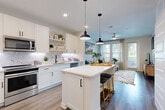 Located in Winter Garden, FL, this well-appointed one-bedroom, one-bathroom residence offers a thoughtfully designed layout with modern finishes throughout. The open-concept kitchen and living area serves as the heart of the home, featuring white shaker cabinetry extending to the ceiling, a marble-inspired subway tile backsplash, stainless steel appliances, and a central island with seating — ideal for both cooking and casual dining. Stylish matte black pendant lights and hardware add a contemporary contrast to the bright, airy palette. Wood-look flooring flows seamlessly throughout the entire space.

The living area is bathed in natural light from large windows and a door leading to a private balcony, complemented by a ceiling fan overhead. The bedroom is generously proportioned, offering ample natural light through large windows and access to two closets, including a spacious walk-in with built-in wire shelving.

The bathroom features a full soaking tub and shower combination with classic white subway tile surround, matte black fixtures, a floating vanity with an undermount sink, and wood-look flooring. Additional conveniences include a dedicated laundry area and a pantry, rounding out this efficiently designed and stylish residence.