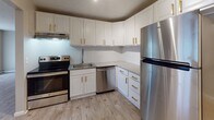 Located at 102 Fort Couch Rd in Bethel Park, PA, this single-floor unit offers a thoughtfully updated interior with a consistent, modern aesthetic throughout. The kitchen stands out as a highlight, featuring crisp white cabinetry with gold-tone hardware, light stone-look countertops, a geometric tile backsplash, and a full suite of stainless steel appliances including a refrigerator, electric range, and dishwasher. Light wood-style flooring runs throughout the entire unit, providing a clean and cohesive look. The living areas are generously proportioned, offering ample room for flexible furniture arrangements. Natural light filters in through windows fitted with blinds and vertical shades, brightening the neutral warm-gray walls. Baseboard heating and wall-mounted AC units are present in the main living spaces for year-round comfort. The unit includes two bathrooms: one features wainscoting, light wood-look flooring, and a clean, functional layout with a toilet and storage; the other is a half-bath with a pedestal-style sink and granite-accented fixtures. The bedrooms are well-sized, each offering closet access and windows with natural light. The overall design is clean, neutral, and move-in ready, making this Bethel Park unit a practical and attractive space.