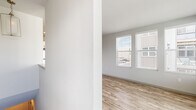 Located in Colorado Springs, CO, this well-designed one-bedroom, one-bathroom unit offers a clean, modern aesthetic with thoughtful finishes throughout. The open-concept kitchen and living area serves as the heart of the home, featuring light wood-style flooring, crisp white shaker cabinets, a subway tile backsplash, quartz countertops, stainless steel appliances, and a kitchen island with pendant lighting overhead. A stacked washer and dryer is conveniently tucked nearby. The living area is bathed in natural light through multiple large windows fitted with blinds, offering views of the surrounding neighborhood. The bedroom is carpeted and includes a ceiling fan and direct access to a generously sized walk-in closet complete with built-in shelving, hanging rods, and a window for added brightness. The full bathroom features wood-style flooring, a vanity with a white countertop, and a glass-enclosed walk-in shower with tile surround. Neutral gray tones, recessed lighting, and consistent finishes create a cohesive and contemporary ambiance throughout the entire space.