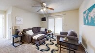 Located at 271 S River Rd in West Lafayette, Indiana, this two-bedroom, one-bathroom unit offers a practical and efficiently designed single-floor layout. The living room serves as the central gathering space, featuring carpeted flooring, a ceiling fan, and a sliding glass door that fills the room with natural light and provides outdoor access. The kitchen is well-equipped with rich, dark wood cabinetry, granite-style countertops, a decorative tile backsplash, and white appliances including a refrigerator, range, built-in microwave, and dishwasher, all set over warm hardwood-style flooring. The full bathroom includes a vanity with wood cabinetry, a stand-up shower with curtain, and hardwood-style flooring. Both bedrooms are carpeted and include ceiling fans with light fixtures. The primary bedroom features dual closets, a window with vertical blinds, and a comfortable, neutral ambiance. The second bedroom offers a large window with natural views to the outdoors, bringing in ample natural light. Throughout the unit, neutral wall tones and practical finishes create a clean, functional living environment well-suited for everyday comfort.