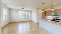 This single-floor residence showcases a clean, modern design throughout its well-planned layout. The open-concept living and dining area is finished with light hardwood-style flooring and receives abundant natural light through large windows offering lush outdoor views. A ceiling fan adds both function and style to the living space, which flows seamlessly into the kitchen.

The kitchen is a standout feature, equipped with grey shaker-style cabinetry accented by gold hardware, white quartz countertops, a classic subway tile backsplash, and a full suite of stainless steel appliances including a range, microwave, dishwasher, and refrigerator. A kitchen island with pendant lighting enhances both prep space and visual appeal.

The bedrooms are carpeted and well-sized, each featuring windows with outdoor greenery views and ceiling fans. The bathrooms are finished with large-format tile flooring, wood-toned vanity cabinetry, white countertops, and gold-framed mirrors. One bathroom provides direct access to a walk-in closet outfitted with wire shelving. A bright, clean hallway with recessed lighting connects the rooms, completing this cohesive and contemporary living space.