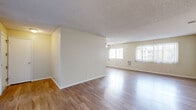 This single-story, 3-bedroom, 1-bathroom home offers a practical and cohesive layout designed for comfortable everyday living. Consistent hardwood-style flooring runs throughout the space, complemented by neutral, warm-toned walls and textured ceilings that lend a classic residential character to every room.

The spacious living area is a highlight of the home, featuring multiple windows dressed with vertical blinds that allow ample natural light to fill the room. A ceiling fan adds both function and charm, while the open feel of the space makes it ideal for both relaxing and entertaining. The layout flows naturally through connecting hallways to the rest of the home.

Each of the three bedrooms is well-proportioned, with large windows providing natural light. The primary bedroom is notably generous in size, and one bedroom features mirrored sliding closet doors, enhancing the sense of space. Additional closets throughout the home provide practical storage solutions.

The kitchen is efficiently designed with white cabinetry, light countertops, and stainless steel appliances including a refrigerator and dishwasher, all set atop wood-style flooring. The bathroom is clean and functional, featuring a full tiled tub-shower combination. A dedicated entrance and connecting hallways round out this thoughtfully organized home.