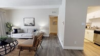 Located at 11148 E Dartmouth Ave in Denver, Colorado, this single-floor residence offers a well-designed layout with a cohesive blend of modern updates and classic architectural character. The living area is a standout space, featuring exposed ceiling beams, a striking whitewashed brick accent wall, and dark hardwood-style flooring that grounds the room. A sliding glass door floods the space with natural light and provides direct access to an outdoor area, enhancing the open, airy ambiance. A second living or flex space connects seamlessly via a hallway, continuing the hardwood-style flooring and neutral color palette. The galley-style kitchen is thoughtfully outfitted with white shaker cabinetry, stainless steel appliances including a refrigerator, range, and microwave, and durable countertops on both sides, offering ample prep and storage space. The bedrooms are carpeted for comfort, with soft neutral tones, exposed ceiling beams, and generous closet space. Large windows in the bedrooms invite natural light and outdoor views. The bathroom features a full tub-shower combination with clean white tile surround and hardwood-style flooring. Throughout the residence, a consistent neutral palette and updated finishes create a welcoming, move-in-ready atmosphere.