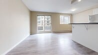 Located at 810 Trillium Park in Sarnia, Ontario, this 2-bedroom, 1-bathroom unit offers a thoughtfully designed single-floor layout with a clean, modern aesthetic. Light-toned laminate flooring flows seamlessly throughout the entire space, complemented by warm beige walls and crisp white trim that create a bright and welcoming ambiance.

The open-concept kitchen and living area forms the heart of the unit. The kitchen is outfitted with white shaker-style cabinetry, dark stone countertops, a subway tile backsplash, a stainless steel refrigerator, and a peninsula with a breakfast bar overhang — ideal for casual dining. The adjoining living room is generously proportioned, bathed in natural light from a large sliding glass door and a secondary window, both offering views of the surrounding neighbourhood.

The primary bedroom is a comfortable size, featuring a closet and a window with natural light. The second bedroom also includes a built-in closet and is finished with the same neutral palette found throughout the unit.

The bathroom is well-appointed with a white vanity, tile flooring, and a full tub-shower combination with tiled surround. Baseboard heating is present throughout, ensuring consistent warmth. This unit combines functional design with modern updates for comfortable everyday living.